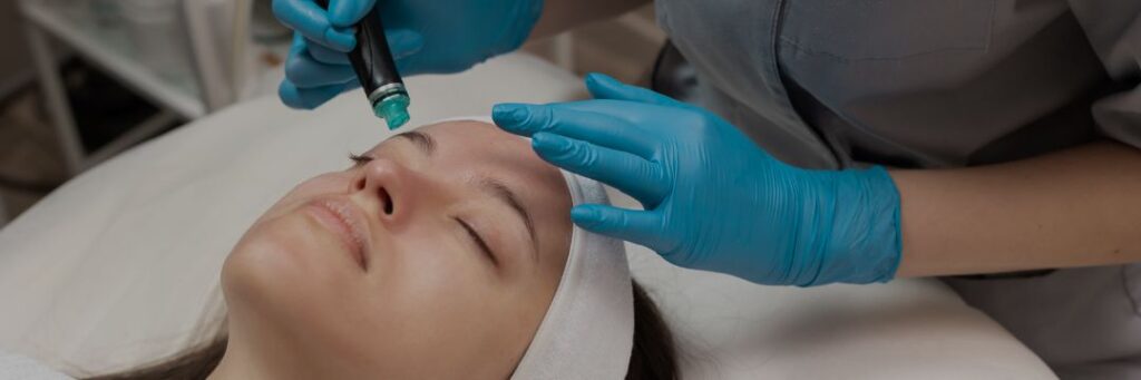 Woman with eyes closed receiving hydrafacial treatment from woman in blue gloves